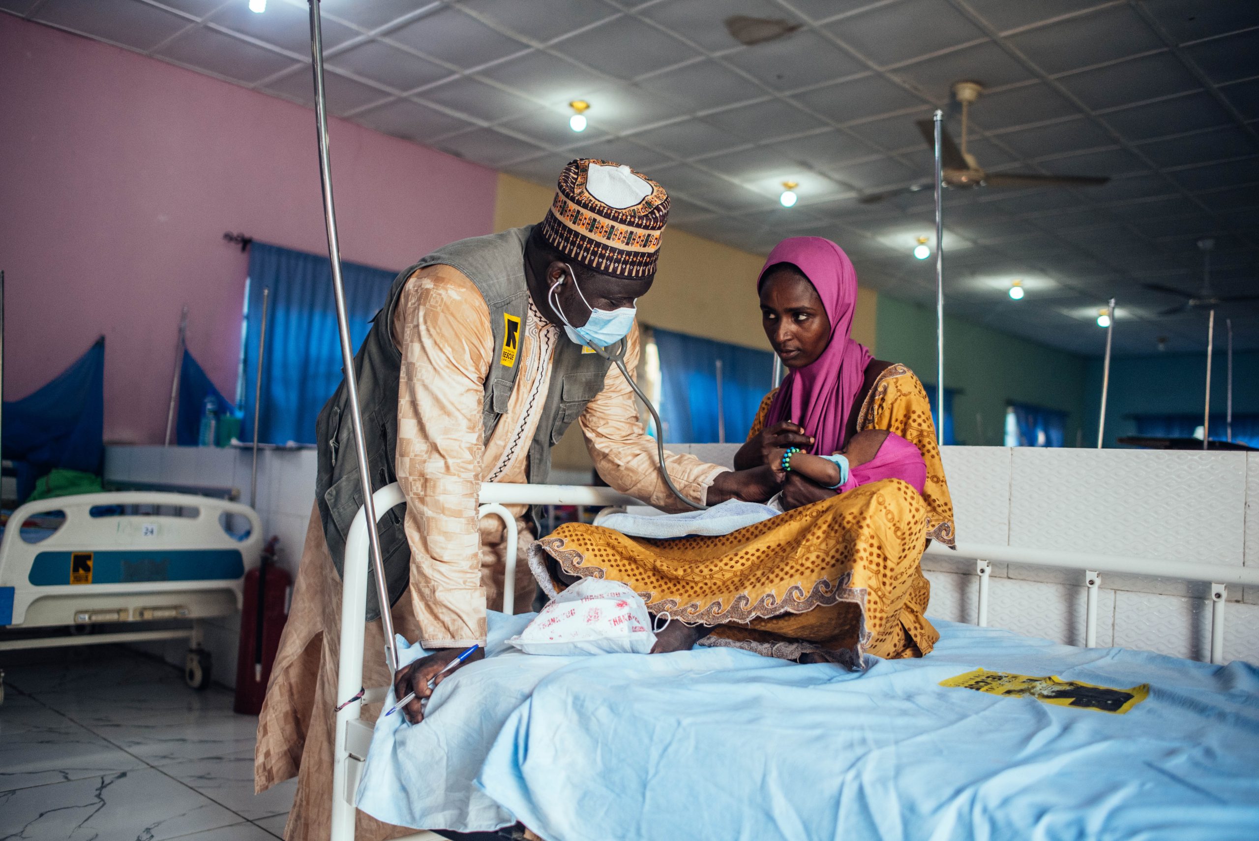 Arts behandeld kind die op schoot van moeder ligt op ziekenhuisbed in Nigeria