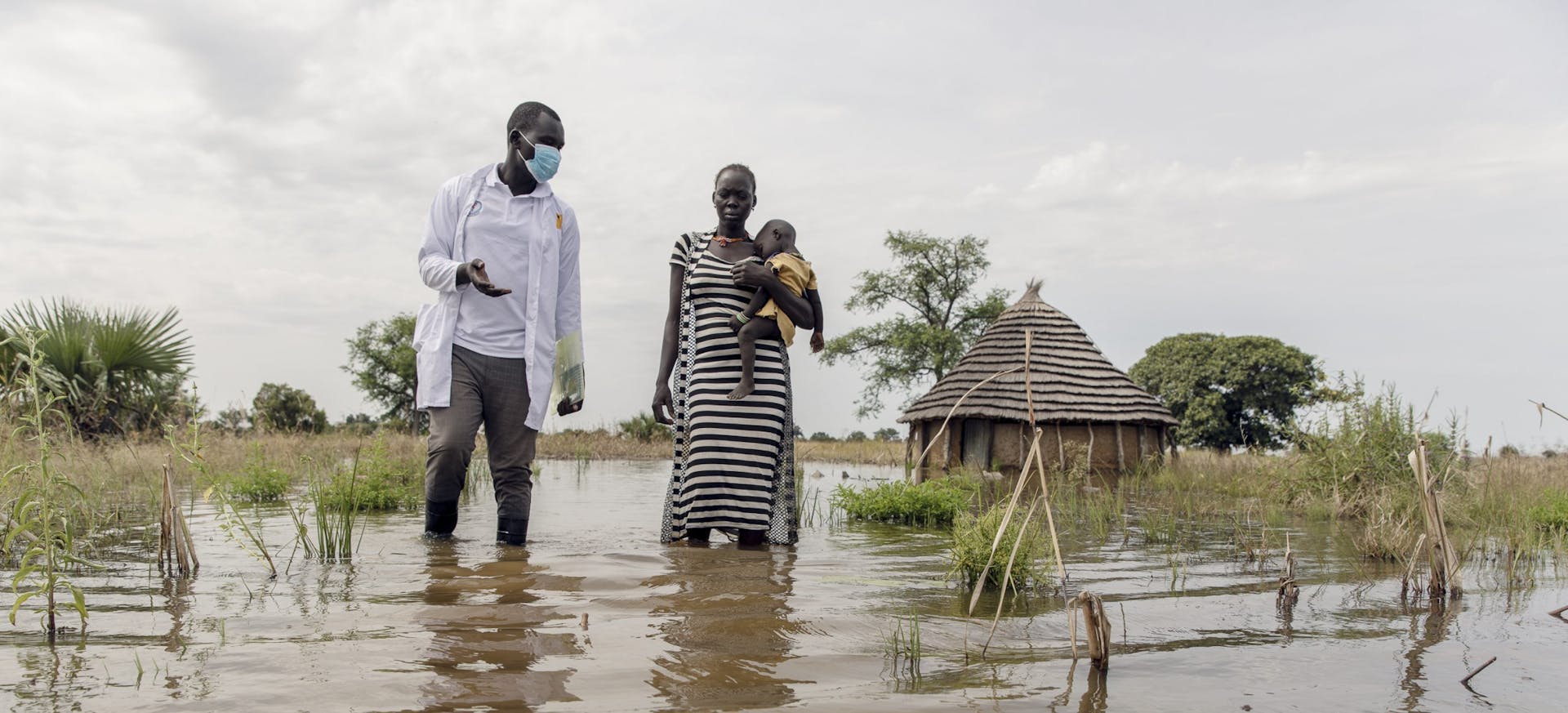 James van IRC en Abuk houden Nyirou vast in de overstromingen rond Abuk's Tukul, in het noorden van Bahr El Ghazal, Zuid-Soedan, zaterdag 16 oktober 2021.