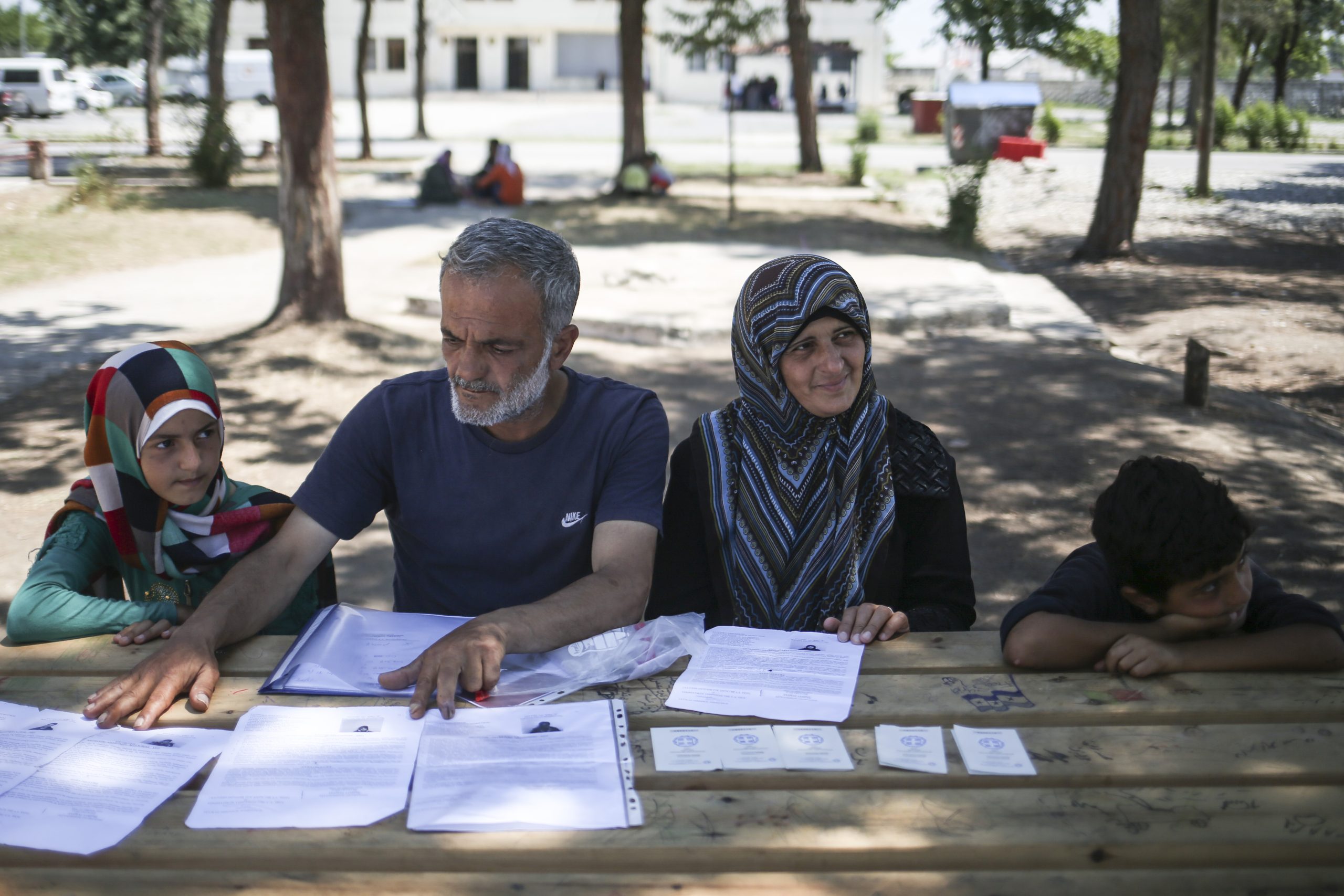 Vrouw en man zitten met hun kinderen achter tafel met daarop documenten om asiel aan te vragen in Duitsland