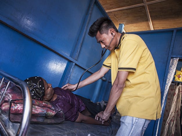 Een arts van een mobiele kliniek onderzoekt een patiënt in een IRC-kampkliniek in het Phwe Yar Kone moslim IDP-kamp in de buitenwijken van Sittwe, in de staat Rakhine.