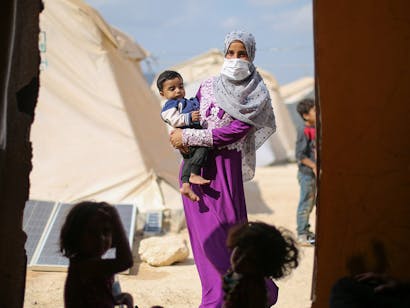 Foto van vrouw met paarse kleding die kind in armen draagt