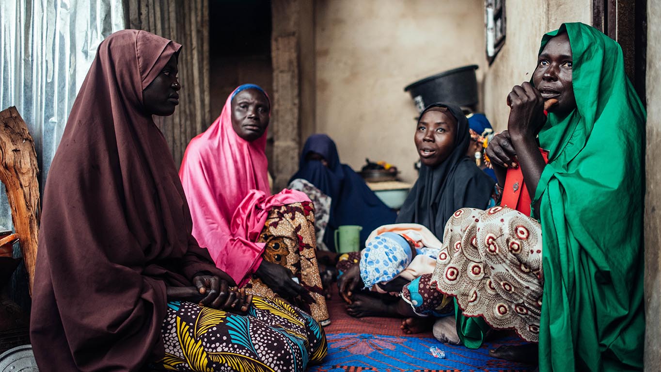 Enkele familieleden en vrienden waren aanwezig bij de doopceremonie van baby Bello Ibrahim in hun huis in Gwoza, Borno, Nigeria op woensdag 22 september 2021. Foto door KC Nwakalor voor IRC Hussiena Ali, werd gedurende haar zwangerschap tot aan de bevalling begeleid in de IRC-faciliteit in Gwoza. Tijdens een van haar routinematige prenatale bezoeken stelde de medische staf van het IRC haar de diagnose zwangerschapshypertensie en werd ze behandeld. Als moeder die voor het eerst moeder werd, leerde ze hoe ze haar baby borstvoeding moest geven, de voordelen van afstand tussen kinderen en gezonde voeding om ondervoeding bij baby's te voorkomen.