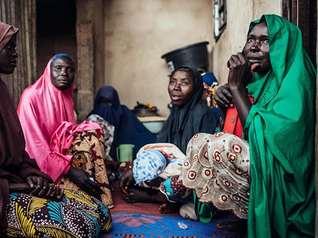 Enkele familieleden en vrienden waren aanwezig bij de doopceremonie van baby Bello Ibrahim in hun huis in Gwoza, Borno, Nigeria op woensdag 22 september 2021. Foto door KC Nwakalor voor IRC Hussiena Ali, werd gedurende haar zwangerschap tot aan de bevalling begeleid in de IRC-faciliteit in Gwoza. Tijdens een van haar routinematige prenatale bezoeken stelde de medische staf van het IRC haar de diagnose zwangerschapshypertensie en werd ze behandeld. Als moeder die voor het eerst moeder werd, leerde ze hoe ze haar baby borstvoeding moest geven, de voordelen van afstand tussen kinderen en gezonde voeding om ondervoeding bij baby's te voorkomen.