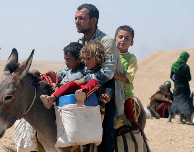 Man zit op ezel met drie kinderen in Irak