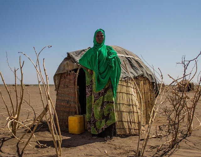 Portretfoto van vrouw die voor hut staat in Ethiopië