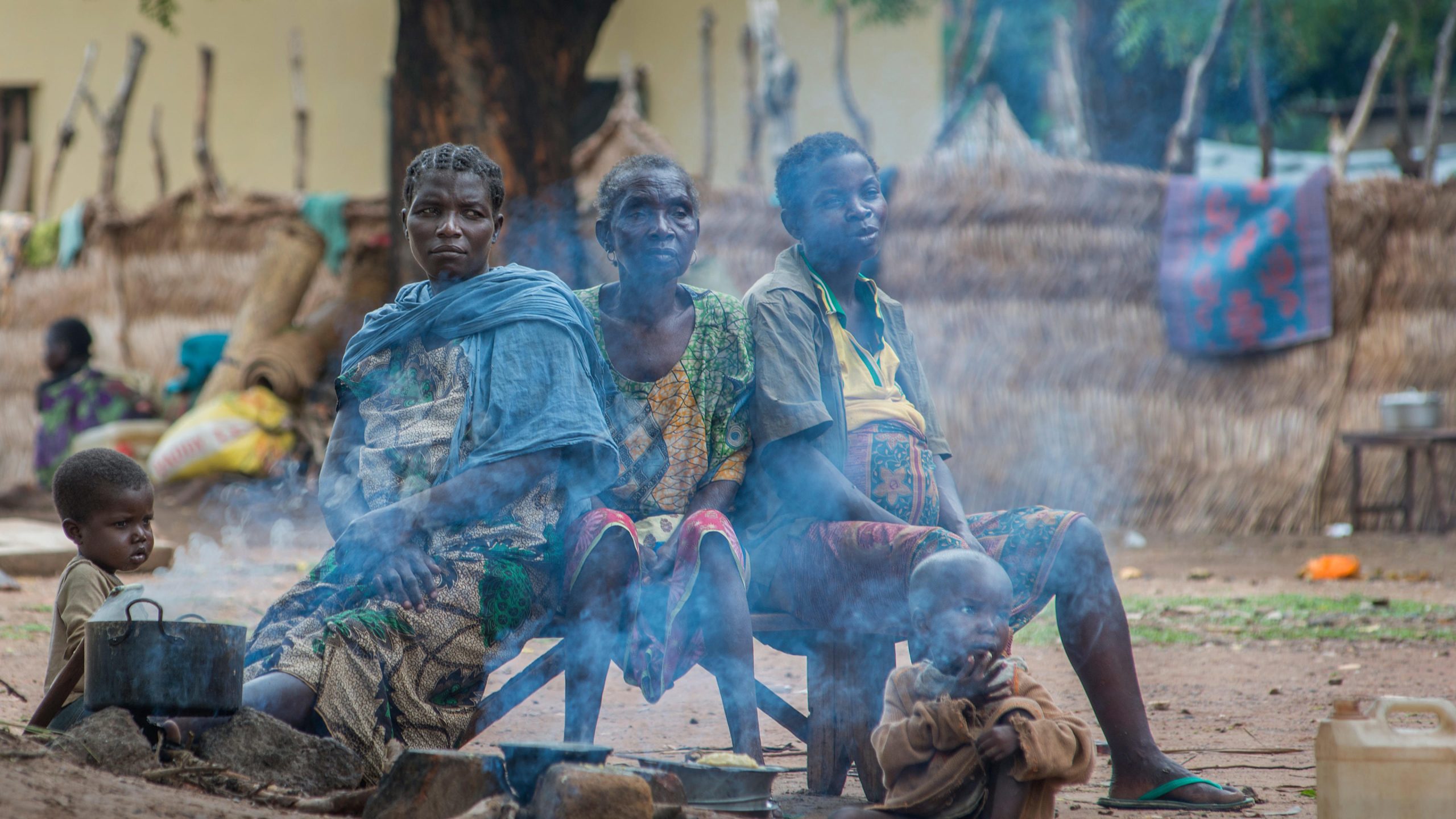 Die vrouwen zitten op bankje bij een pan waar rook uit komt in Centraal Afrikaanse Republiek