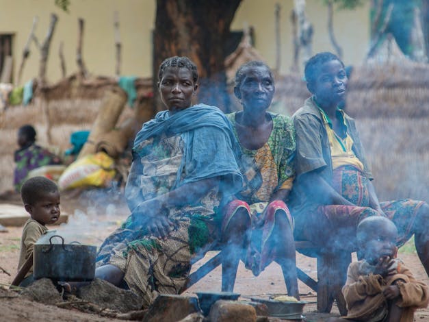 Die vrouwen zitten op bankje bij een pan waar rook uit komt in Centraal Afrikaanse Republiek