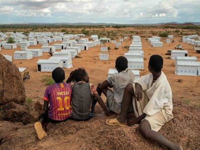 Vier jongens kijken over vluchtelingenkamp in Tsjaad