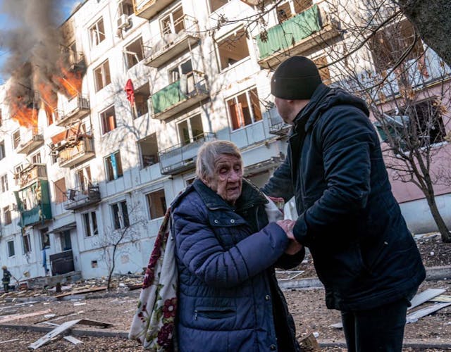 Man houdt vrouw vast met brandend gebouw op de achtergrond in Oekraïne