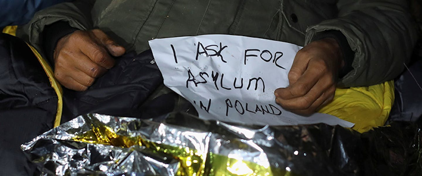 Een migrant houdt poster vast waarin hij vraagt om asiel in Polen
