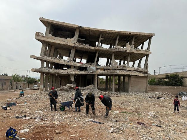 Hulpverleners zijn aan het wel met bijl en kruiwagen voor verwoest gebouw in Turkije