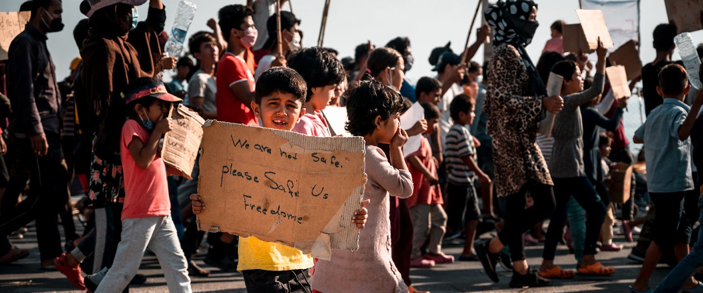 Protest van migranten. Jongen houdt kartonnen bord vast met boodschap
