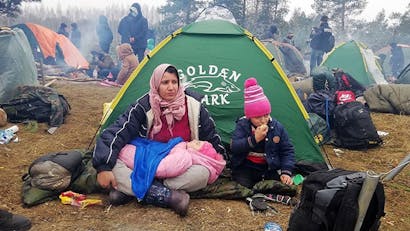 Kinderen zitten voor tent in grensgebied Wit-Rusland en Polen