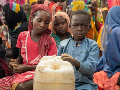 Kind met jerrycan in drukke menigte