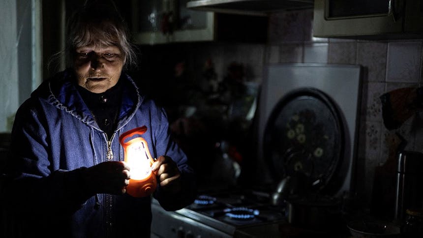 Vrouw houdt lampje vast in een donker huis in Oekraïne