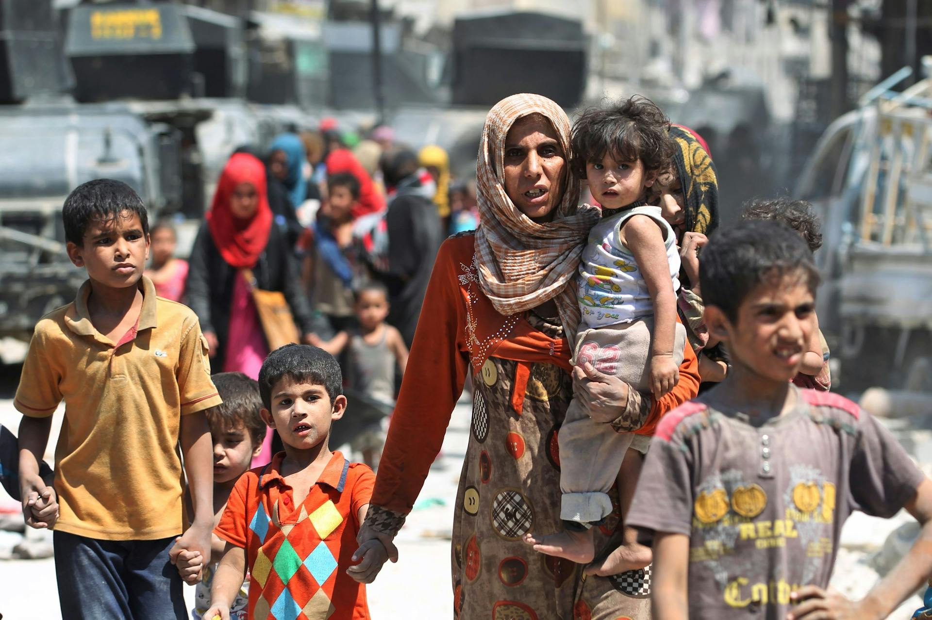 Foto van moeder met kind in haar arm en hand in hand met ander kind in Iraq