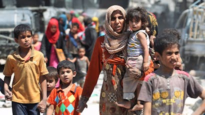 Moeder met kind in haar arm en ander kind aan haar hand op de vlucht in Iraq