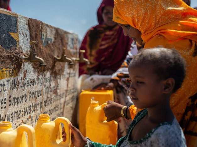 Somalische kinderen staan met een jerrycan bij een drinkwaterpunt.