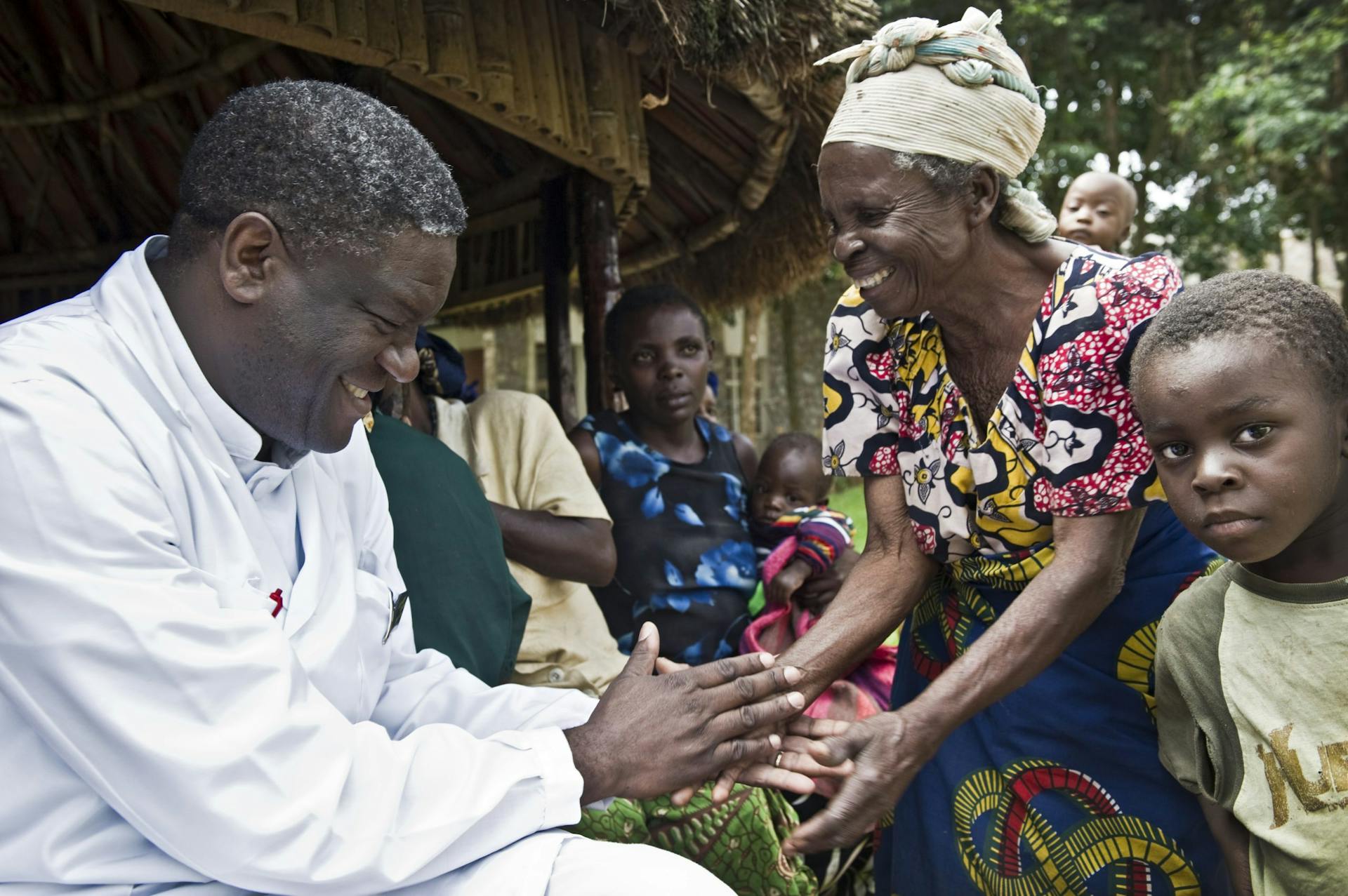 Dr. Mukwege schudt de hand van vrouw met beide een lach op hun gezicht