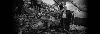 Vrouw staat met armen open op verwoestingen van aardbeving in Turkije en Syrië