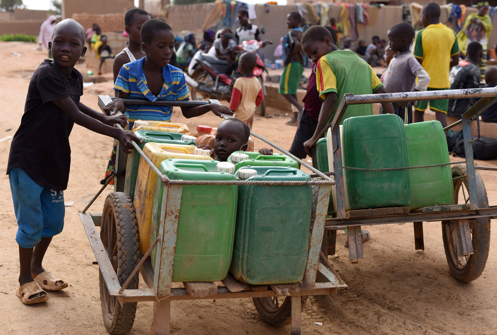 Kinderen duwen karren met watercontainers in Burkina Faso