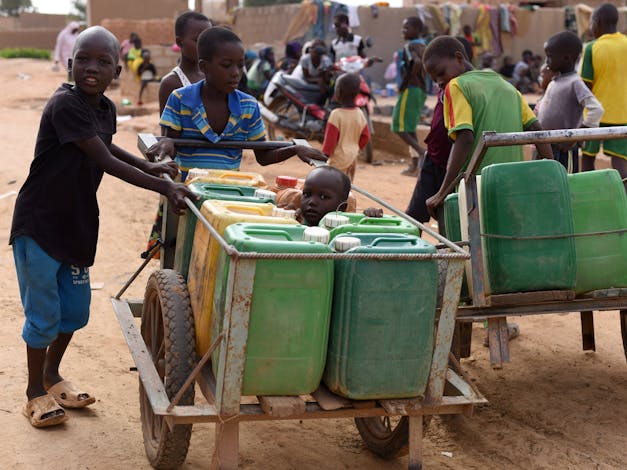 Kinderen duwen karren met watercontainers in Burkina Faso