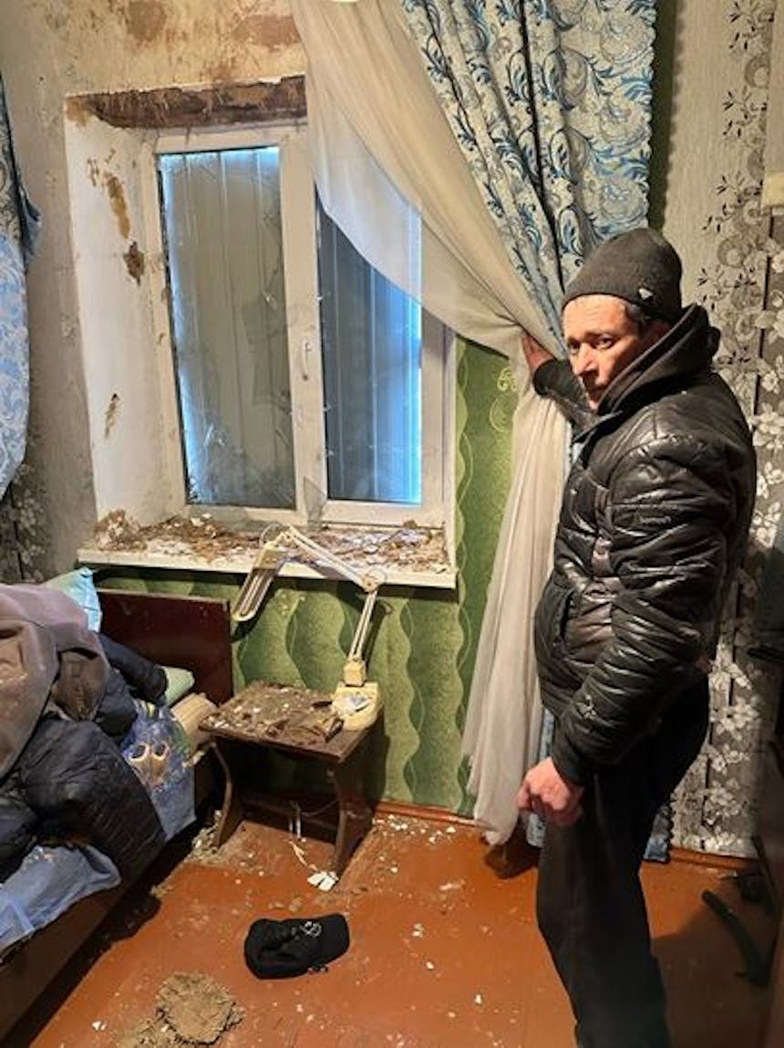 Mand die verwoest raam en kozijn in Oekraïne laat zien