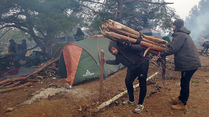 Man draagt boomstammen op zijn rug in grensgebied Wit-Rusland en Polen