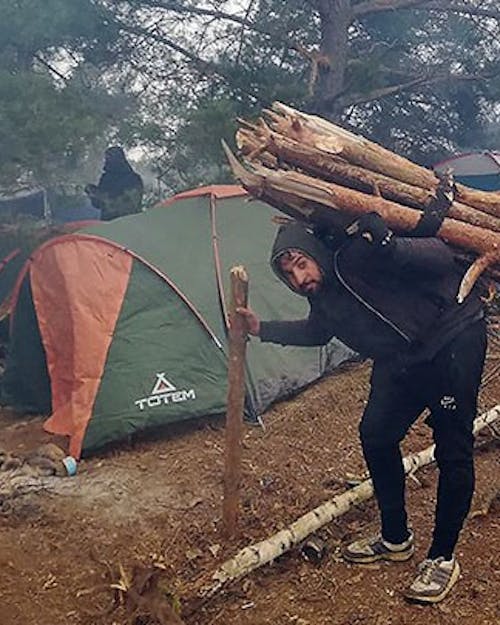 Man draagt boomstammen op zijn rug in grensgebied Wit-Rusland en Polen