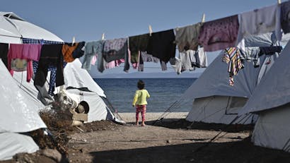 Meisje staat tussen tenten in bij de zee