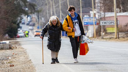 Jongeman helpt vrouw met lopen