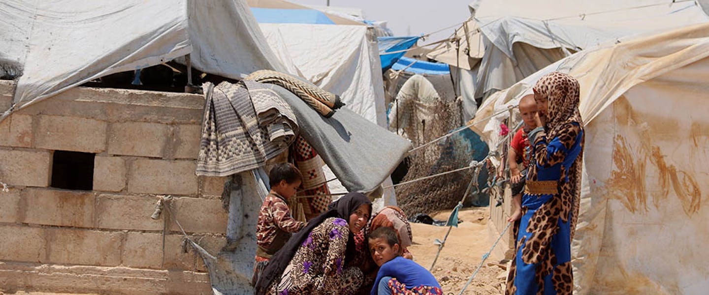 Familie hurkt gezamenlijk bij vluchtelingenkamp