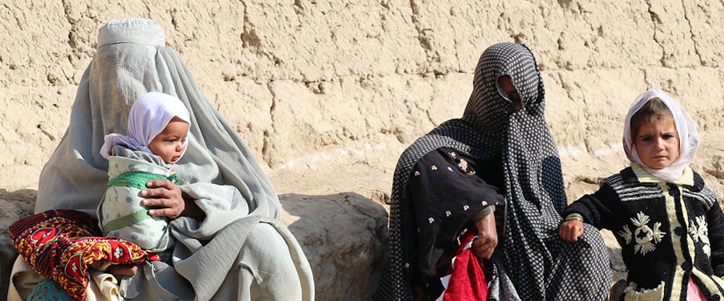 Familie zit op de grond in de hitte en bedekken gezichten met boerka