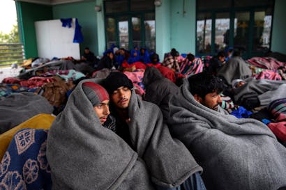 Vluchtelingen en migranten proberen zich te warmen terwijl ze pauzeren bij een benzinestation voordat ze hun tocht naar de Hongaarse grens opgeven, in de stad Indjija, Servië 5 oktober 2016. REUTERS/Marko Djurica