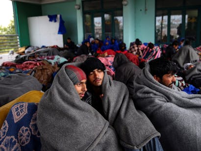 Vluchtelingen en migranten proberen zich te warmen terwijl ze pauzeren bij een benzinestation voordat ze hun tocht naar de Hongaarse grens opgeven, in de stad Indjija, Servië 5 oktober 2016. REUTERS/Marko Djurica