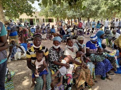 Groep mensen zitten met hun baby's op hun schoot in Burkina Faso