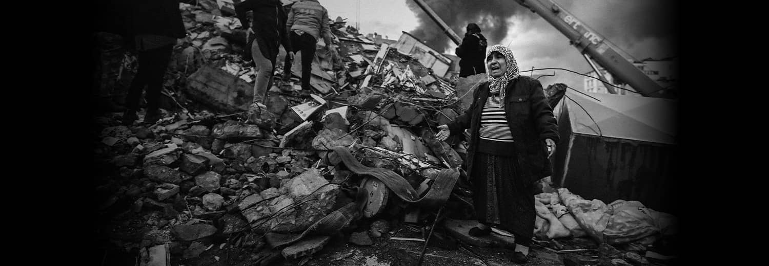 Vrouw lijkt om hulp te schreeuwen met armen wijd en staat op enorme hoop van puin