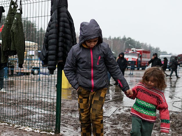 Twee kinderen lopen hand in hand bij de Wit-Russische en Poolse grens