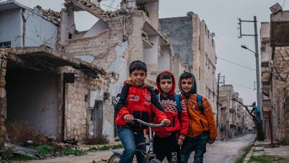 Drie jongens in verwoeste stad Aleppo