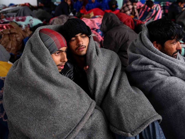 Vluchtelingen houden zichzelf warm door zichzelf in te wikkelen met dekens