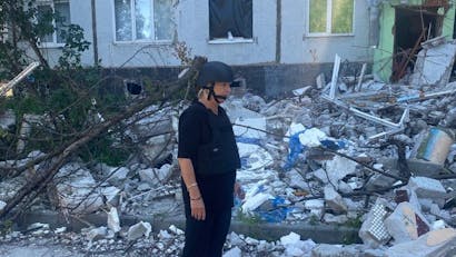 Foto van Tineke met helm op in Oekraïne met verwoeste omgeving