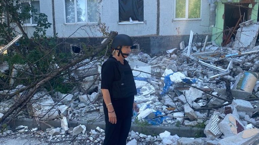 Foto van Tineke met helm op in Oekraïne met verwoeste omgeving