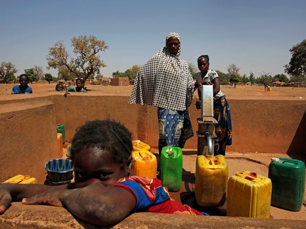 Vrouw vult water van een waterpomp in het dorp Nedgo