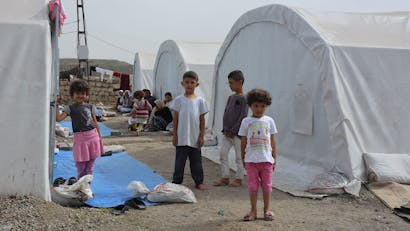 Kinderen staan voor tent in vluchtelingenkamp