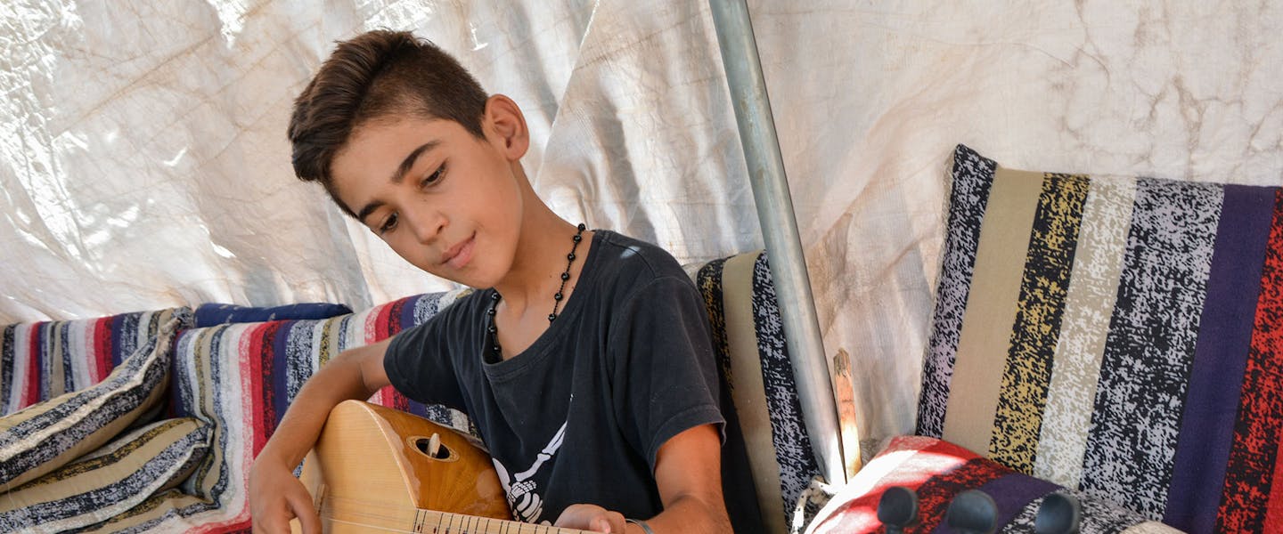 Jongen speelt op instrument in Syrië