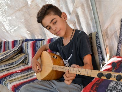 Jongen speelt op instrument in Syrië