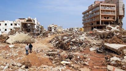 Mannen lopen langs puin van gebouwen veroorzaakt door overstromingen in Derna, Oost-Libië, op 11 september 2023. Overstromingen in het oosten van Libië hebben alleen al in de kuststad Derna aan de Middellandse Zee aan meer dan 2300 mensen het leven gekost, zeiden de hulpdiensten van de regering in Tripoli op 12 september.