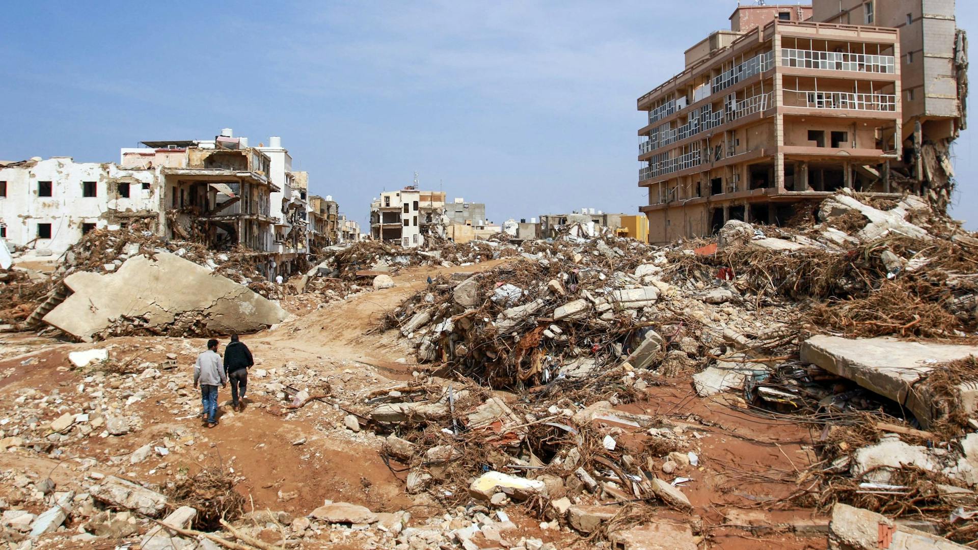 Mannen lopen langs puin van gebouwen veroorzaakt door overstromingen in Derna, Oost-Libië, op 11 september 2023. Overstromingen in het oosten van Libië hebben alleen al in de kuststad Derna aan de Middellandse Zee aan meer dan 2300 mensen het leven gekost, zeiden de hulpdiensten van de regering in Tripoli op 12 september.