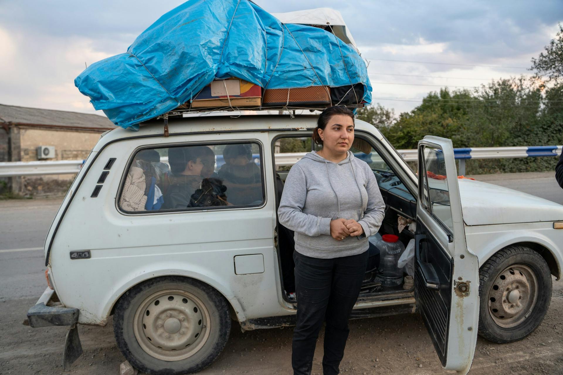 mensen staan voor een witte auto waarin ze gevlucht zijn uit Nagorno-Karabach