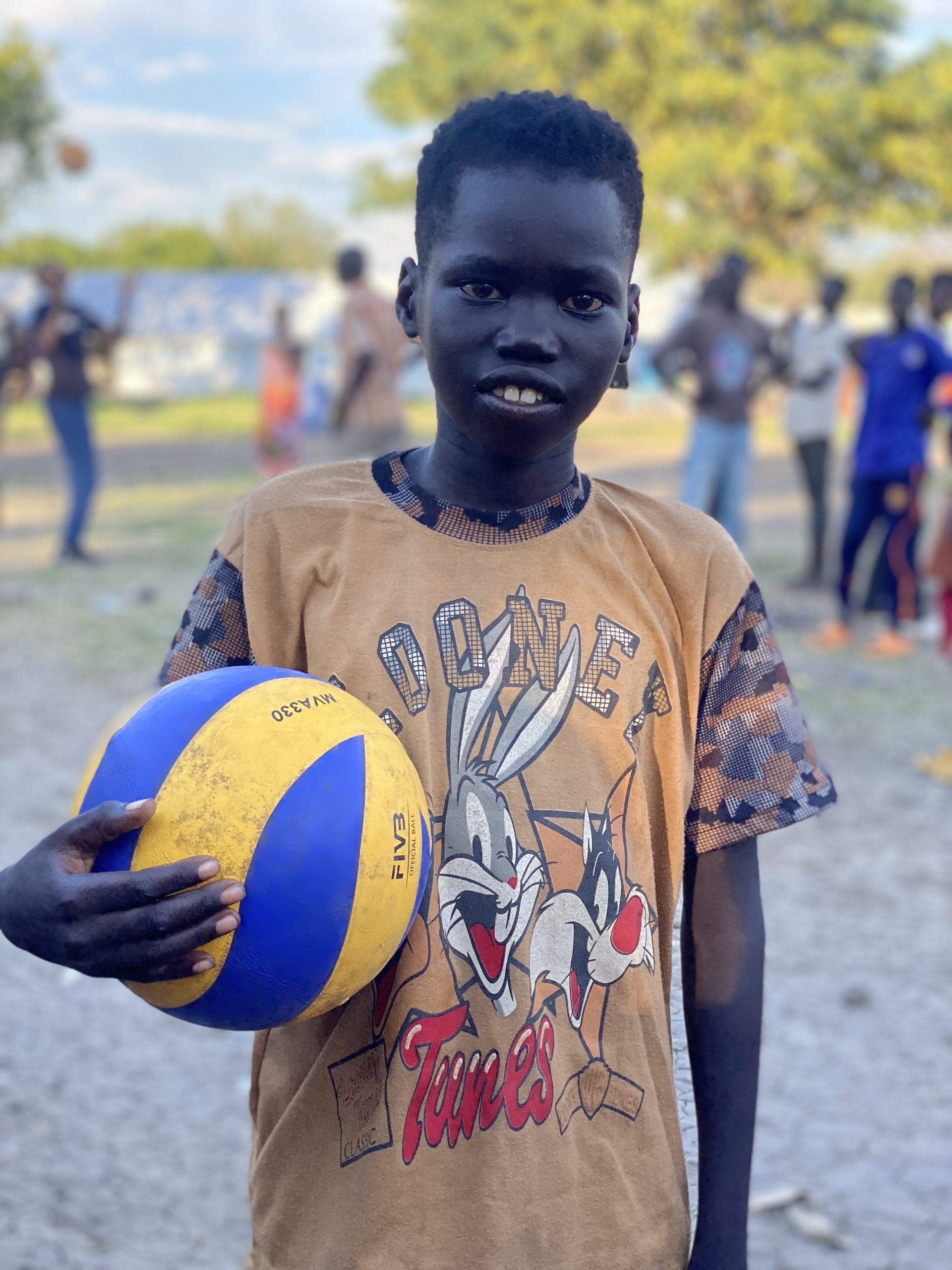 Foto van een jongen in Zuid-Soedan met een bal en een Looney Tunes shirt